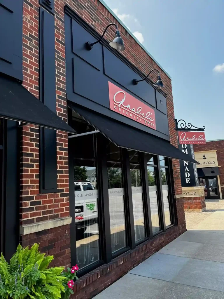 Exterior view of Anabel's Oriental Rugs store showcasing a brick facade, large windows, and a prominent sign.